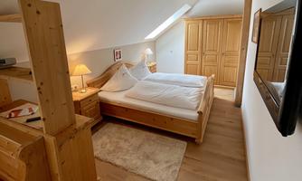 A cozy room with wood paneling and a double bed. The room is bright and simply furnished.