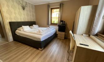 A cozy bedroom with a large bed and modern furniture. There is a desk and windows that provide plenty of daylight.