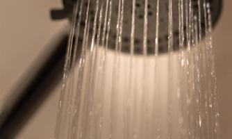 A modern showerhead with water that flows down evenly. The gentle water streams create a relaxing atmosphere.