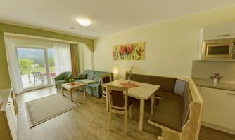 A bright living room with a cozy couch and a dining area. Large windows offer a view of nature.