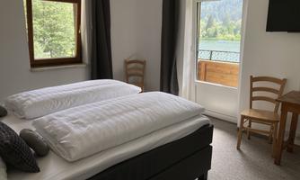 A cozy bedroom with two single beds and a window that offers a view of nature. There is also a small table with chairs.