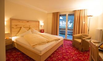 A bright bedroom with a large bed and comfortable pillows. The room has a balcony and is furnished with stylish furniture.