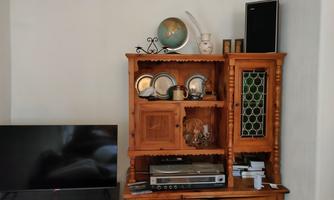 A wooden cabinet with a globe, plates, and a television. Below it is a device for playing music.