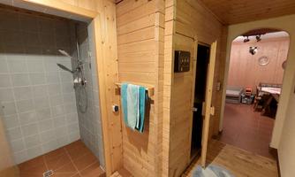 A cozy sauna and shower area with wooden paneling. The room is bright and inviting, perfect for relaxing.