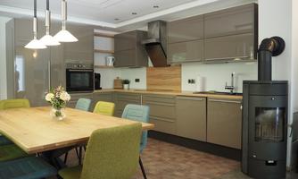 A modern kitchen with elegant gray cabinets and a large wooden row. Colorful chairs are around the table, along with a flower vase for an inviting look.
