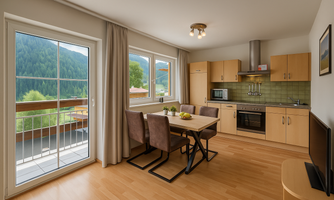 A bright kitchen with a dining area and modern appliances. Large windows provide a beautiful view of the green landscape.
