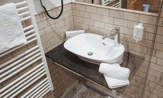 A modern bathroom with an elegant sink and a towel holder. The walls are decorated with bright tiles.