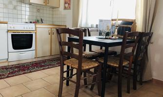 A bright kitchen with a table and four chairs. In the background, kitchen cabinets and a stovetop are visible.