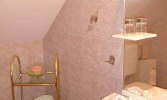 A small bathroom with tiled walls. There are towels on a rack and a sink with a mirror above it.