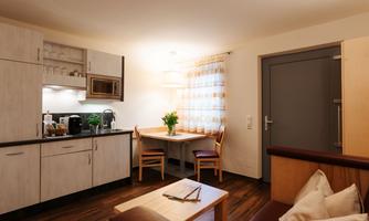 A cozy kitchen with a dining area. In the background, there is a table and chairs, and the walls are painted light.