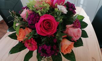 A colorful bouquet with different roses and other flowers. The colors range from pink to purple and create a cheerful atmosphere.