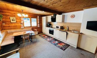 A cozy kitchen with wooden elements and a dining table. The amenities include a stove, a microwave, and a television.