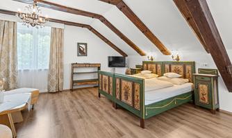 A cozy bedroom with a large, intricately decorated bed.  
Large windows let in plenty of light, and the wooden beams give the room a rustic charm.