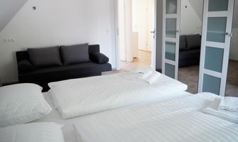 A cozy bedroom with a double bed and a sofa. The room is bright and furnished in a modern style.