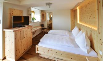 A cozy bedroom with wooden furniture and two single beds. A television and a chair are also present in the room.