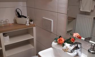 A modern bathroom with a sink, a mirror, and stylish decor. There is a bright atmosphere and well-organized storage spaces.
