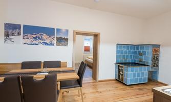 A modern kitchenette with blue tiles and a dining table. Pictures of mountains are hanging on the wall.