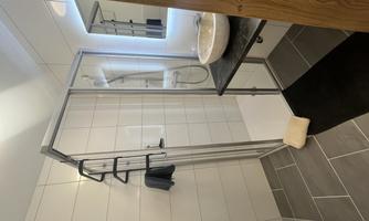 A modern shower with clear tiles and an elegant sink. The room feels bright and inviting.