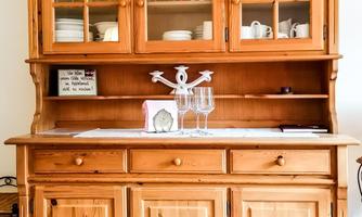 A rustic wooden cabinet with glass fronts. On the top shelf, there are dishes and decorations.