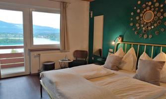 A cozy room with a large bed and elegant decor. The view of the landscape and the lake through the window is stunning.