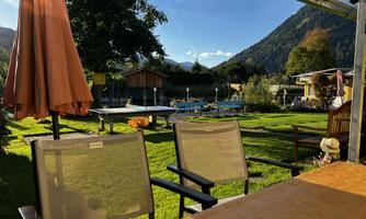 A cozy garden with a swimming pool and a view of the mountains. Chairs and a parasol invite you to relax.