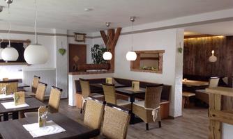 A modern restaurant with wooden decor and cozy seating areas. Bright lighting and plant accents create an inviting atmosphere.