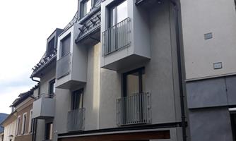 A modern building with a gray facade and balconies. The architecture is simple and contemporary.