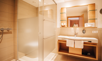 A modern bathroom with an elegant shower and a bright sink. The walls are in warm tones and there is plenty of natural light.