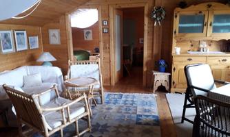 A cozy room with wooden paneling, a seating area, and a dining table. The decor feels inviting and rustic.