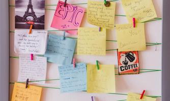 A colorful notice board with various sticky notes and clips. In the background, there is an image of the Eiffel Tower.