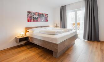 A modern bedroom with a large double bed and a cozy atmosphere.  
Large windows provide plenty of daylight and a view to the outside.