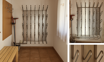 A practical ski boot dryer in a cozy apartment. The wall is equipped with hooks for ski equipment, and there is a wooden bench for sitting.