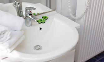 A modern sink with a faucet and white towels. Green decor in the form of flowers provides a fresh accent.