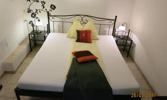A simple bedroom with a black metal bed and fresh bedding.  
Next to the bed are nightstands with lamps.