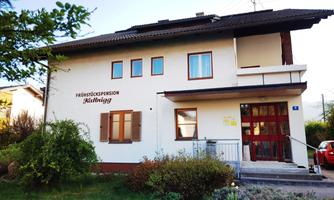 A cozy bed and breakfast building with an inviting entrance. Surrounded by green spaces and shrubs.