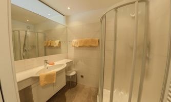 A modern bathroom with a shower and a sink. There are bright walls and towels in yellow.