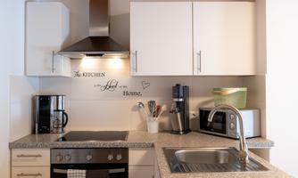 A modern kitchen with bright cabinets and an elegant countertop. On the countertop are a coffee maker, a blender, and other kitchen utensils.