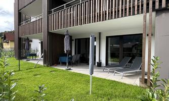 A modern terrace with loungers and sun umbrellas. The lawn is well-maintained and invites relaxation.