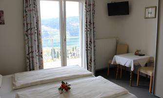 A bright room with two single beds and a table. Large windows offer a view of the landscape.