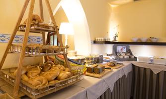 A buffet with freshly baked bread on a wooden rack. In the background, there are more dishes and a cozy atmosphere visible.