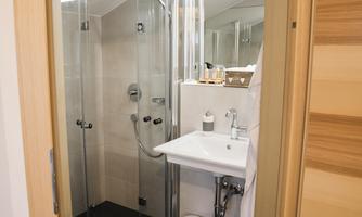 A modern bathroom with a glass shower and a sink. The walls are brightly tiled, and the space feels clean and inviting.