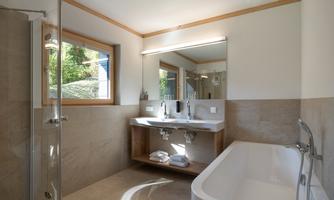 A modern bathroom with a shower and a freestanding bathtub. A large mirror and bright wooden details create an inviting atmosphere.
