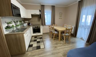 A modern kitchen with a dining area and large windows. The room is bright and tastefully furnished.