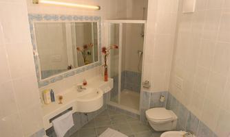 A modern bathroom with white tiles and blue accents. It features a shower, a sink, and decorative elements.