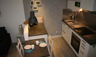 A modern kitchen with a dining area. The table is set with plates and glasses.