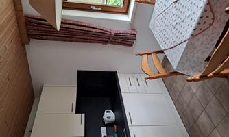 A bright kitchen with modern furniture and a dining table. The window lets in daylight and offers a view outside.