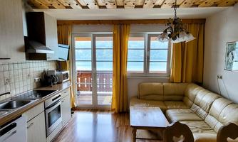 A cozy vacation apartment with a modern kitchen and a bright living area. Large windows offer a view of a beautiful outdoor area.