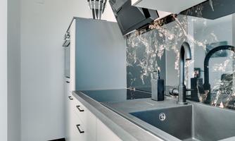 A modern kitchen with elegant black and white surfaces. The equipment includes a faucet and a sink that are well integrated into the space.