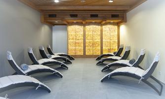 A relaxing wellness area with loungers and a salt stone wall. The atmosphere is calm and inviting.