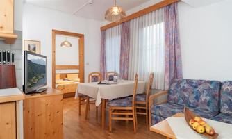 A cozy living area with wooden interiors and a dining table. The room is bright and friendly with a beautiful view.